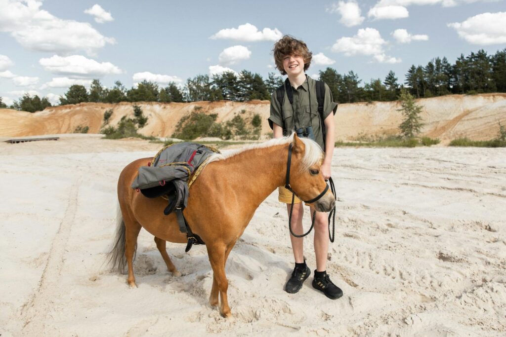 Teenage boy smiling while standing with a pony