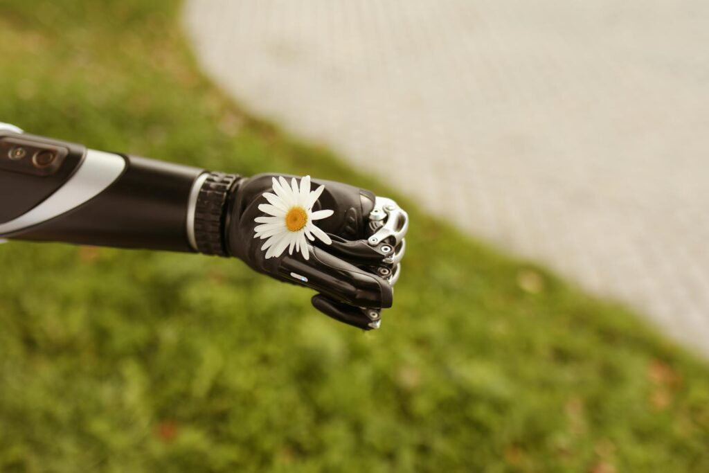 Close-up of a prosthetic hand gently holding a daisy, symbolizing technology and nature.