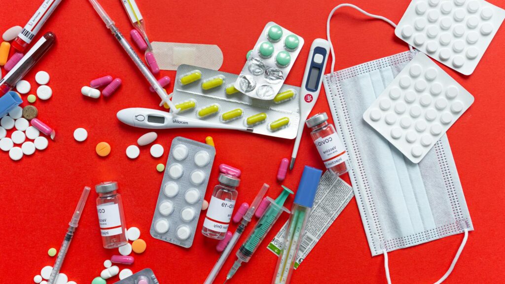 Medical supplies and medications displayed on a red background, emphasizing healthcare essentials.