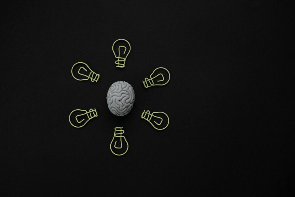 Conceptual photo of a brain surrounded by light bulb clips on black background.
