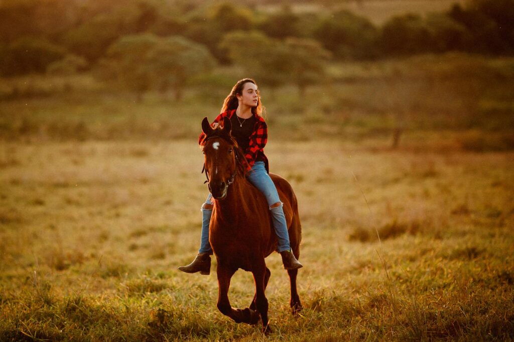 Young woman in a plaid shirt riding a brown horse