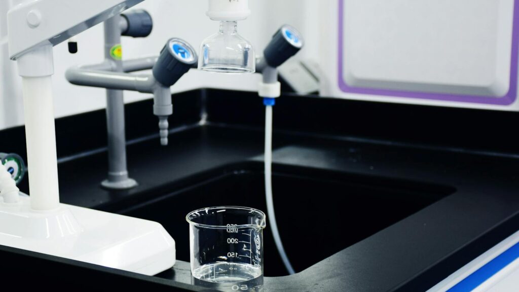 Close-up of laboratory equipment used for water filtration, featuring beakers and faucets.