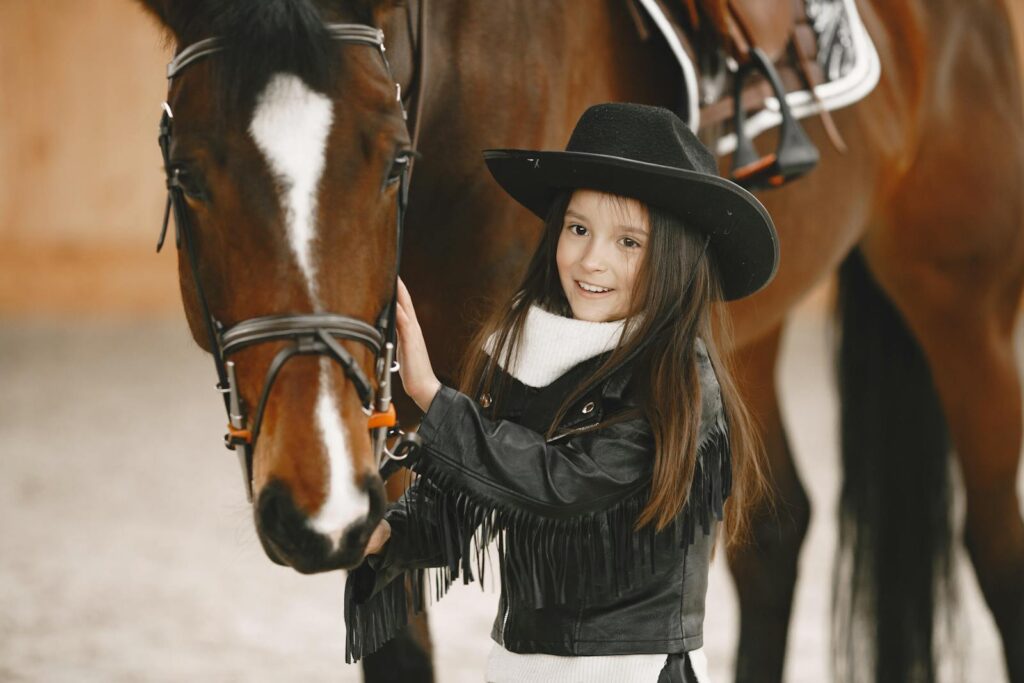 Cheerful young girl in a cowboy hat pose with her horse