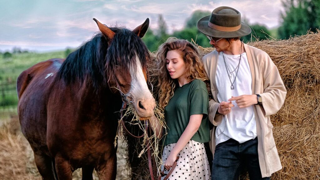 A couple enjoying a serene rural moment with a horse by haystacks