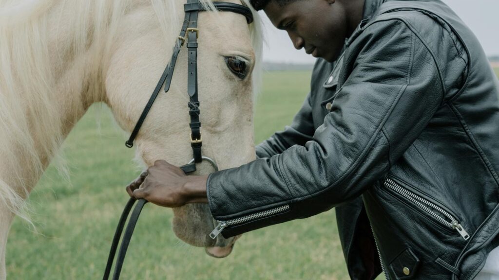 African American man gently interacting with a white horse outdoors.