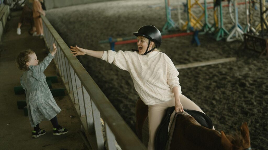 A joyful moment between a mother and child at an indoor horse riding stable, embracing connection and adventure.