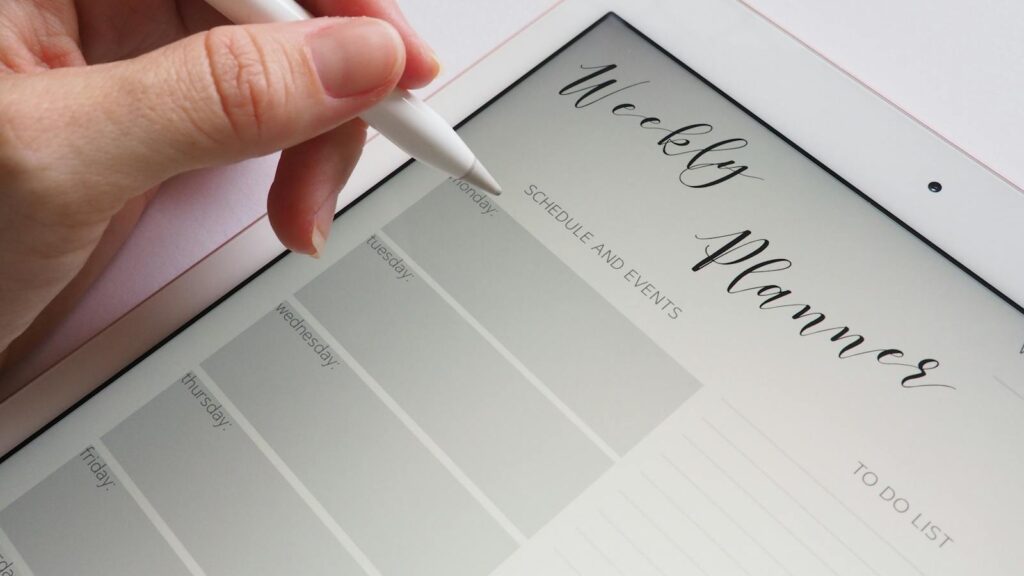 A stylus writing in a digital weekly planner on a tablet screen, ideal for organization.