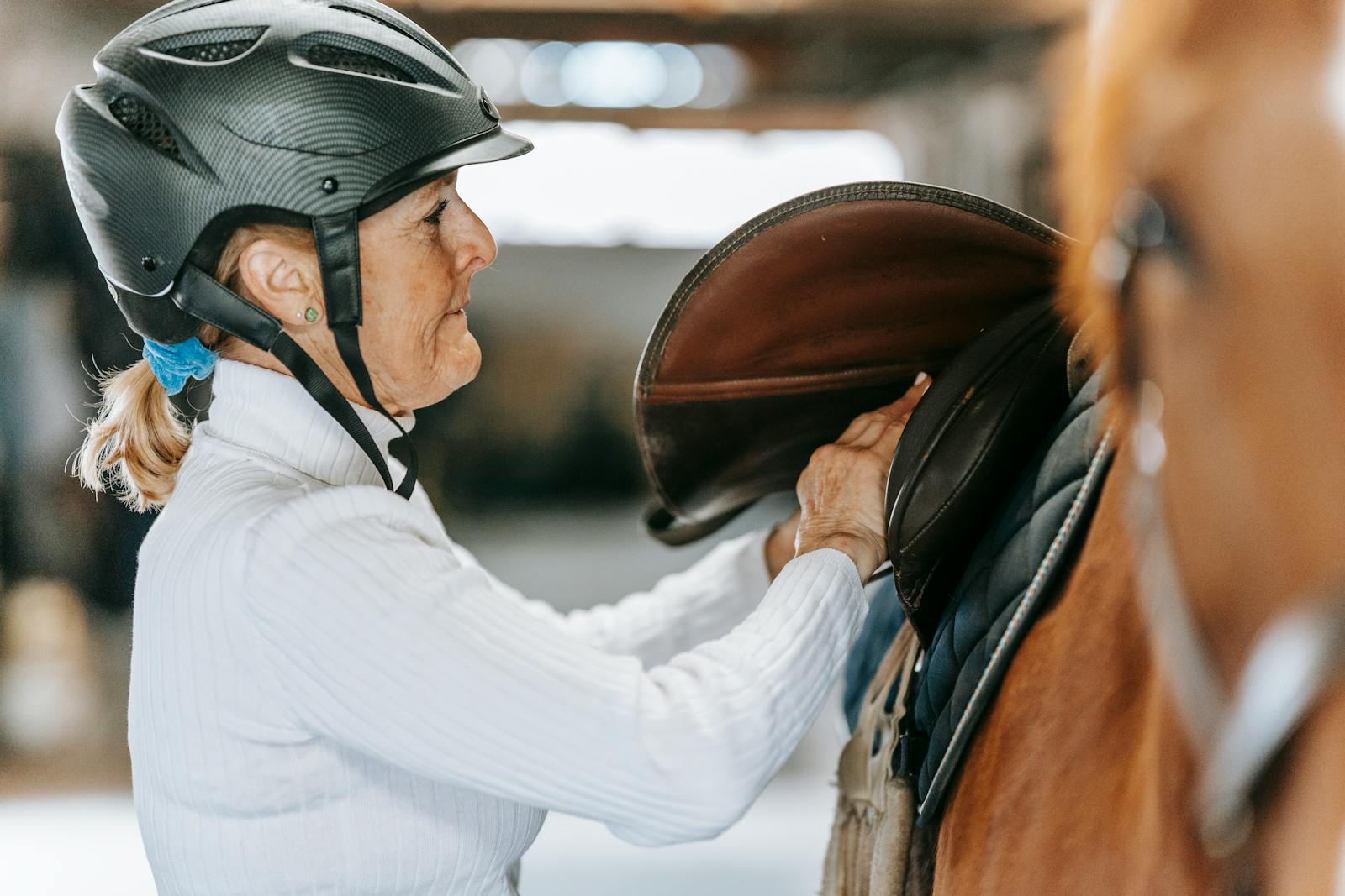 Woman prepares horse for riding