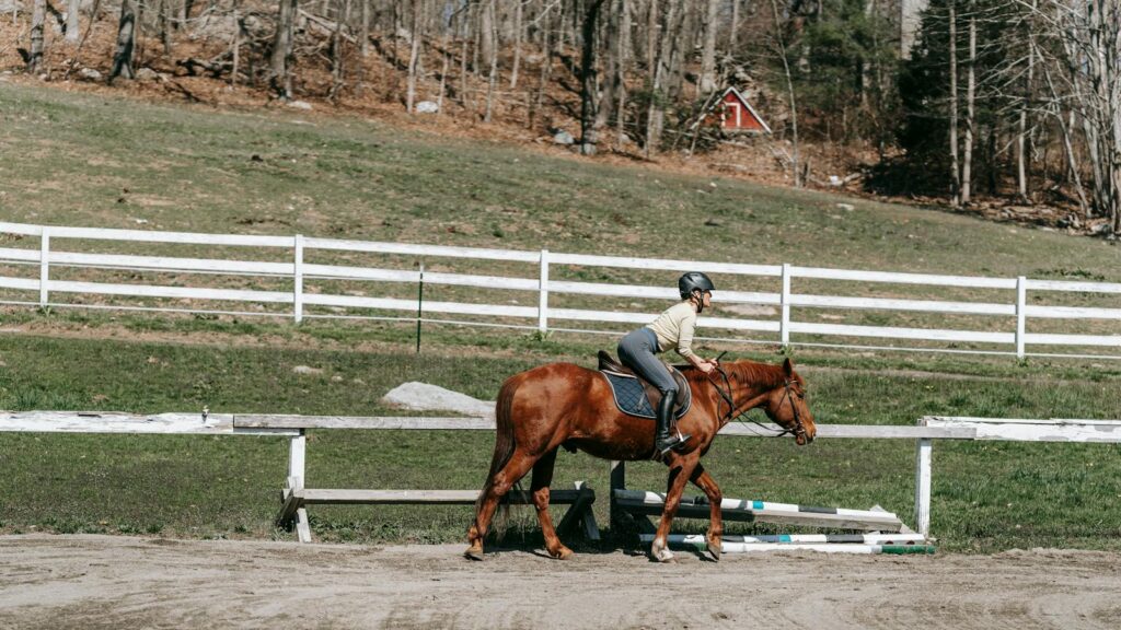 A woman riding a horse in a rustic paddock scene outdoors in spring.