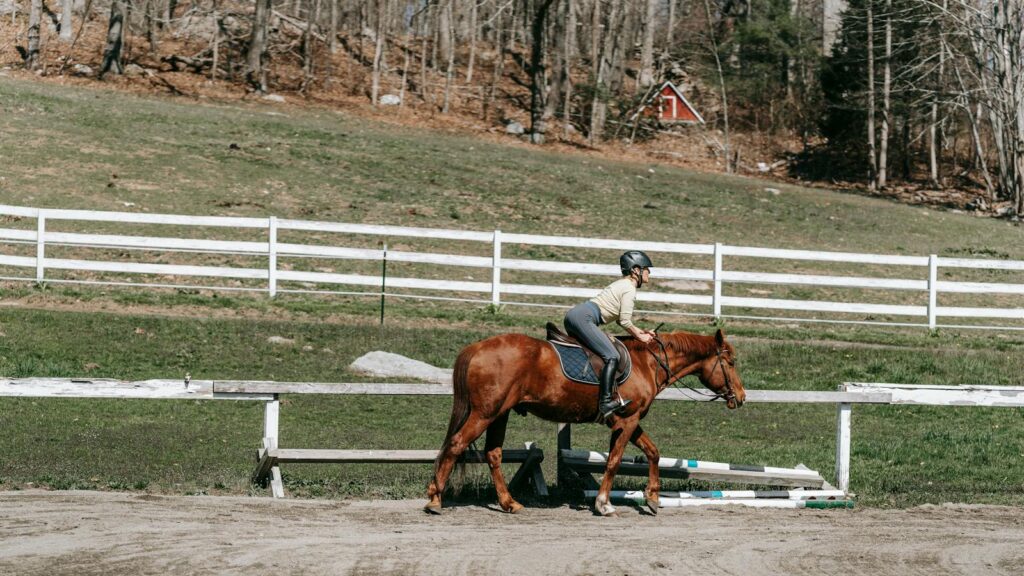 A woman riding a horse in a rustic paddock scene outdoors in spring.