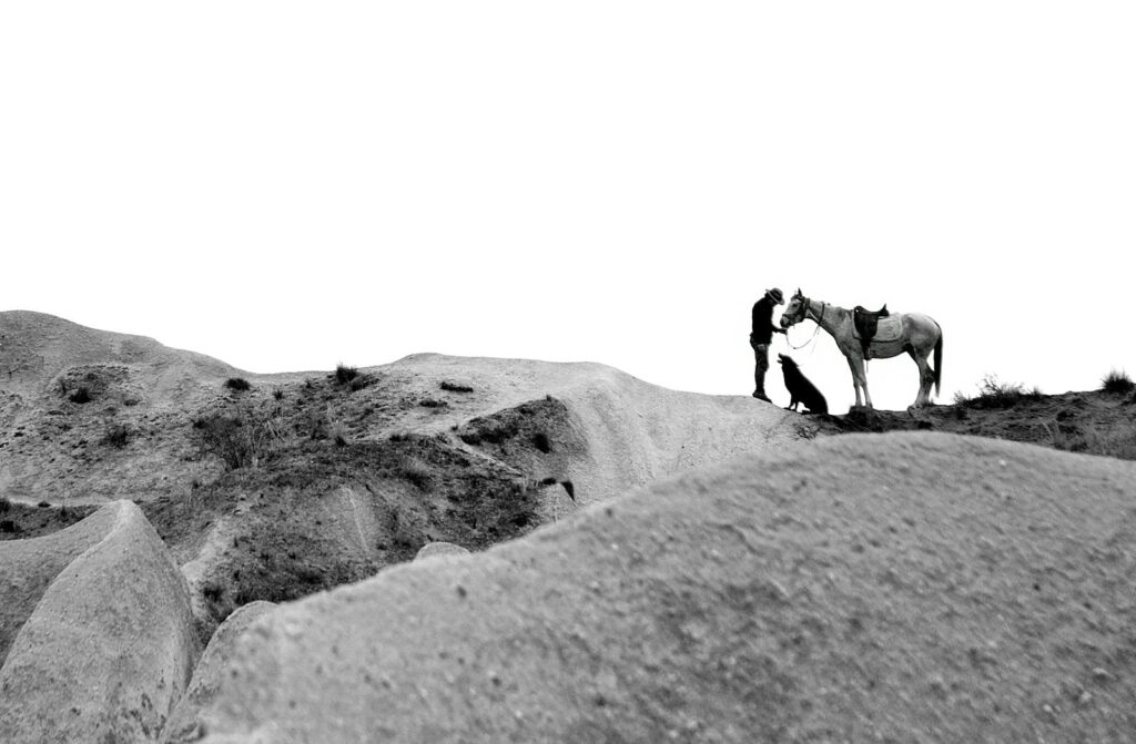 Black and white image of a man with a horse on rocky terrain in Nevşehir, Türkiye.