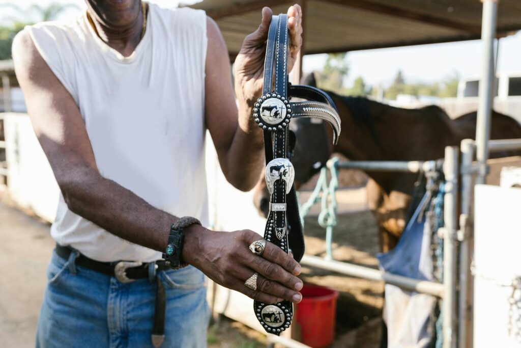 Man holding decorative horse harness, showcasing equestrian equipment outdoors.