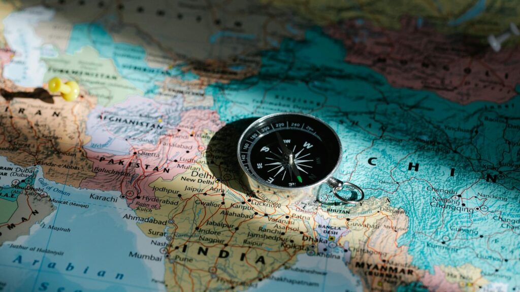 Close-up image of compass on a world map highlighting travel direction and exploration.
