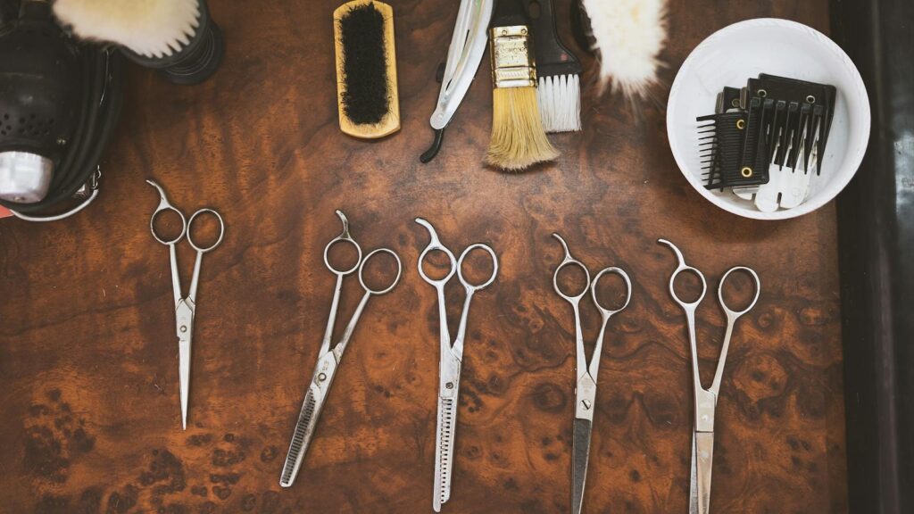 A collection of vintage barber tools including scissors and brushes on a wooden surface.