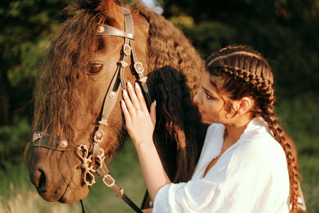 Woman with braided hair gently touches her horse