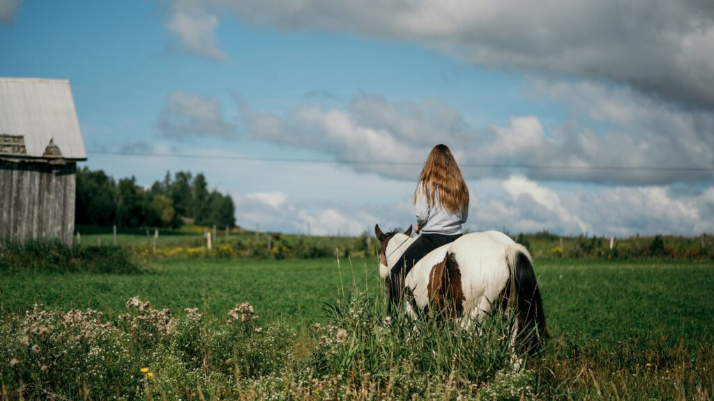 a woman riding on the back of a white and brown horse