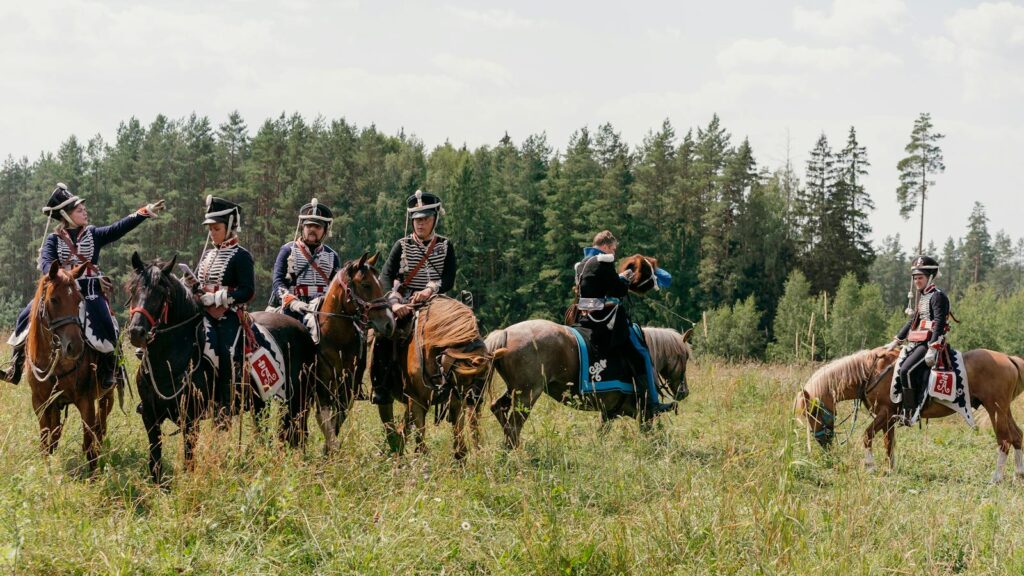 Group of soldiers on horseback in historical military uniforms during a reenactment outdoors.