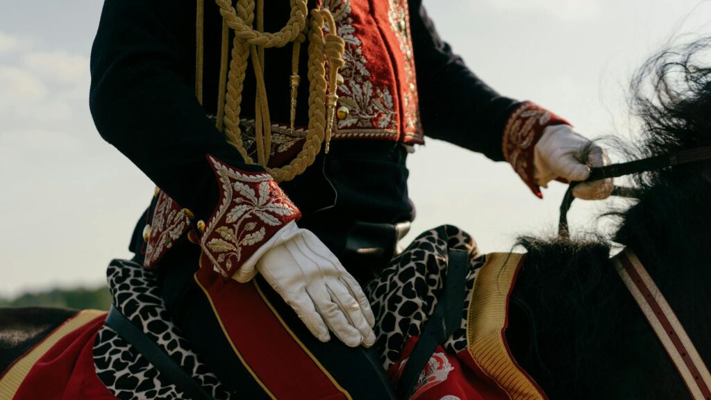 traditional hussar cavalry uniform with intricate details, mounted on a horse outdoors.