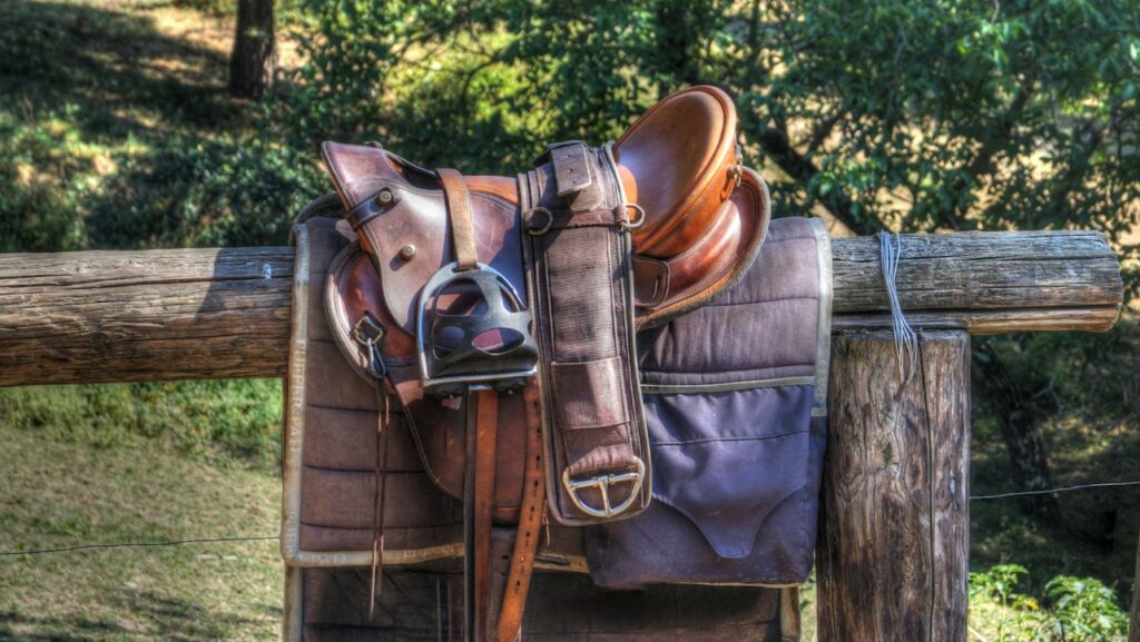 brown leather horse saddle on fence
