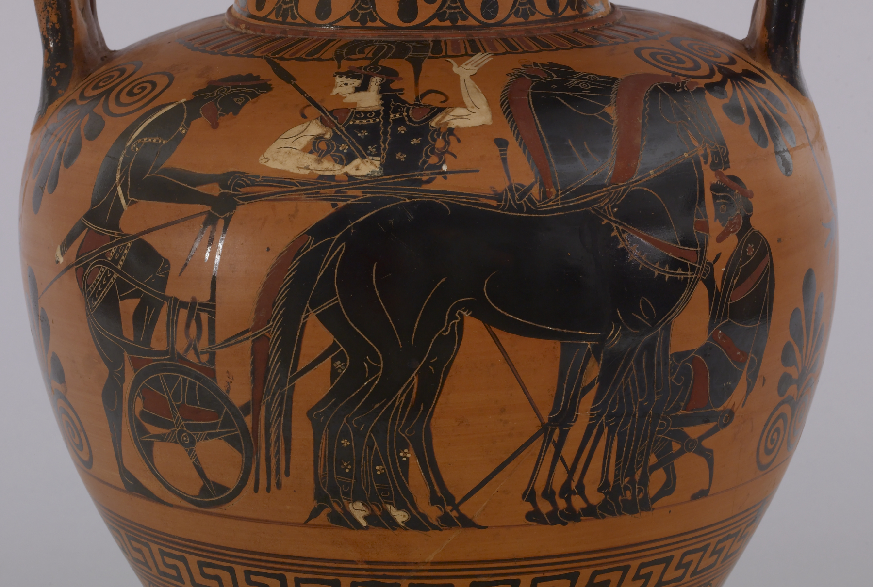On one side of this black-figure amphora, a bearded man in a short chiton is mounting a chariot while grasping the reins of four horses. between 530 and 520 BC