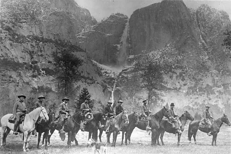 Nine park rangers called the first rangers of Yosemite National Park, shown mounted on horses lined up in meadow in Yosemite Valley, 1915