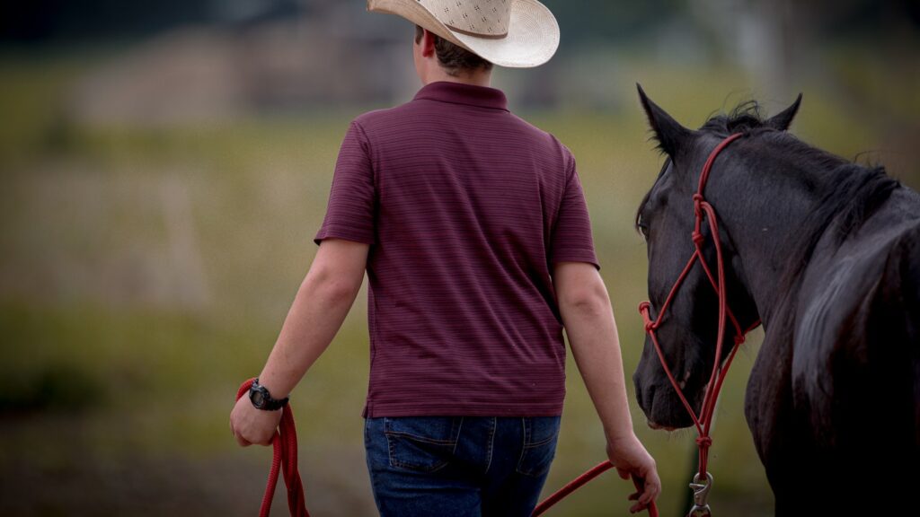 a man in a cowboy hat walking a horse