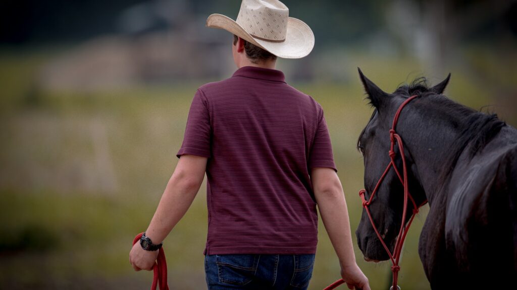 a man in a cowboy hat walking a horse