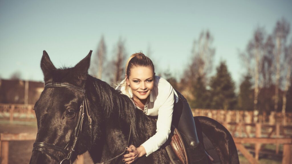 woman in white hoodie riding black horse
