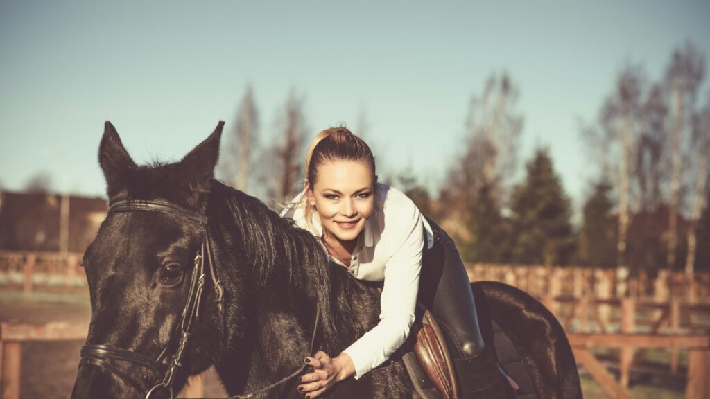 woman in white hoodie riding black horse