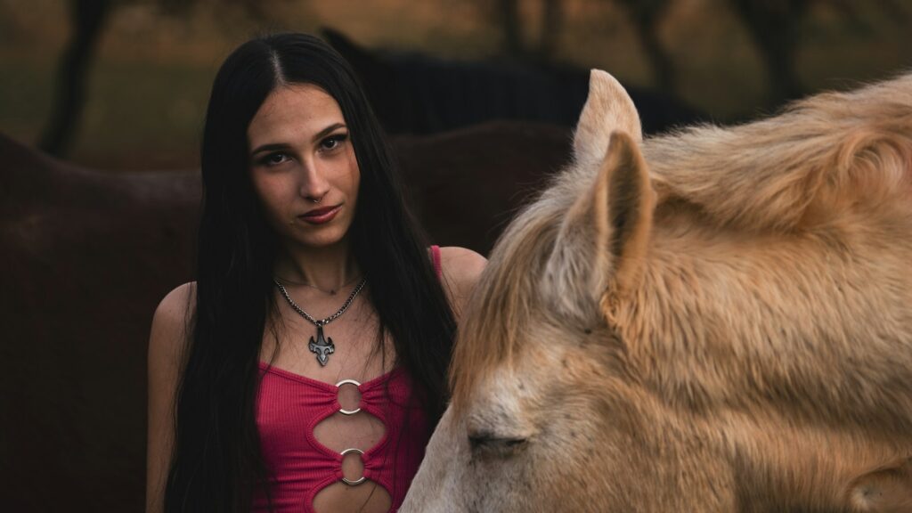 A woman standing next to a brown horse