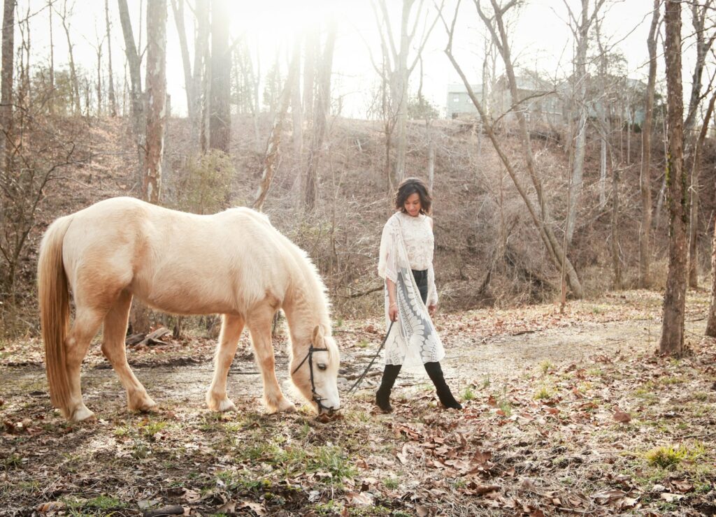 Woman wearing black boots besides white horse