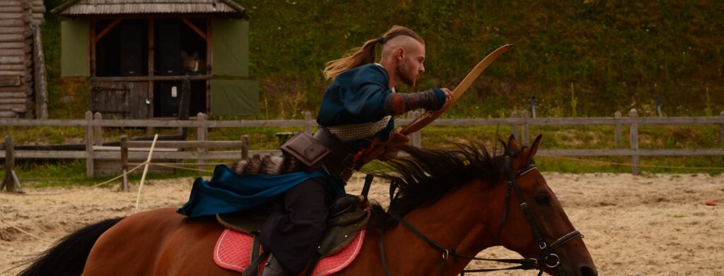Woman in blue jacket riding brown horse during daytime