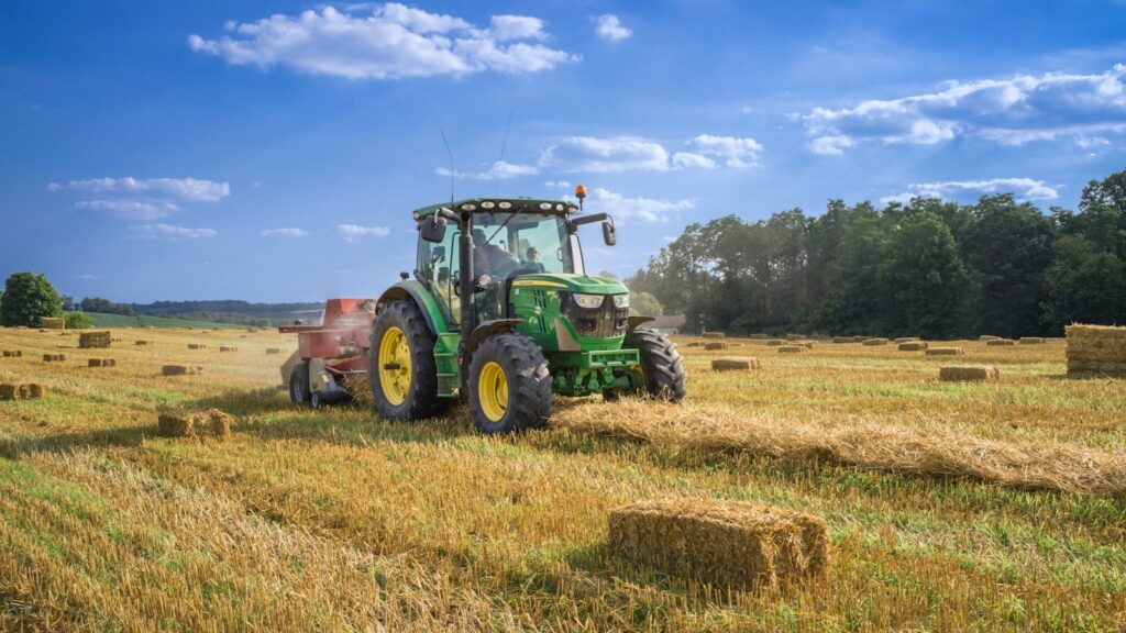 green tractor on brown grass field under blue sky during daytime