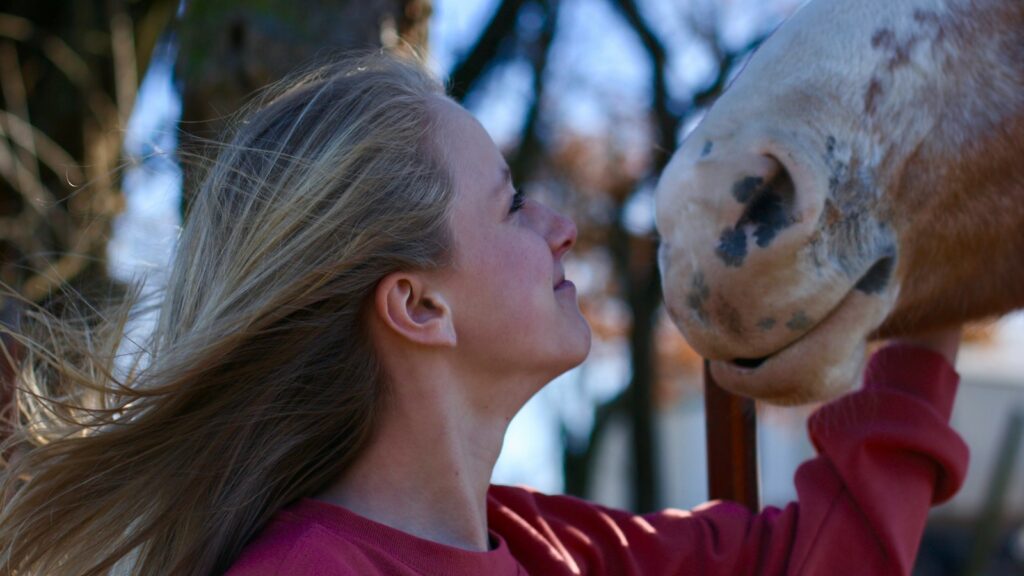 Portrait of woman looking at beige horse