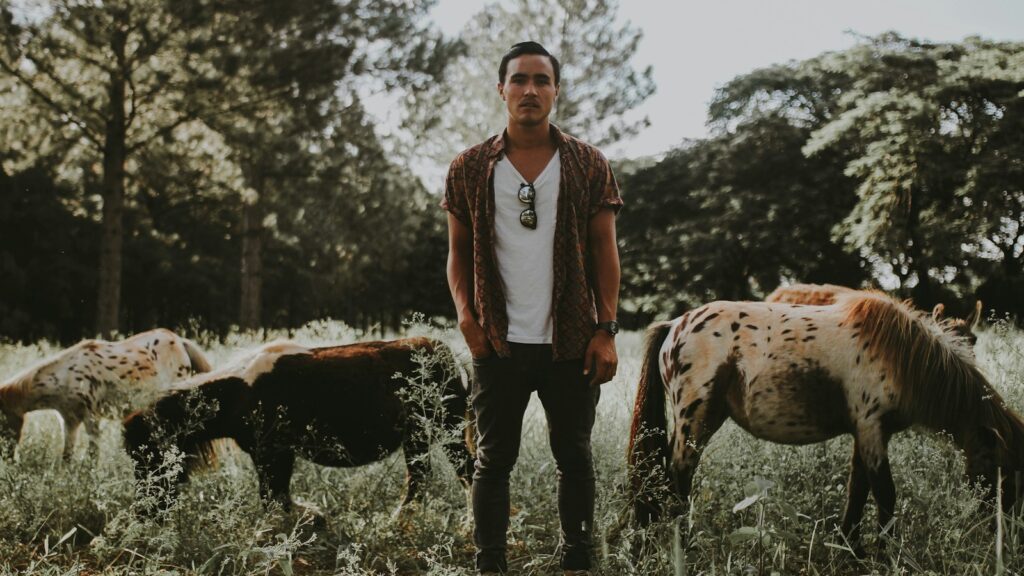 man standing between horse during daytime