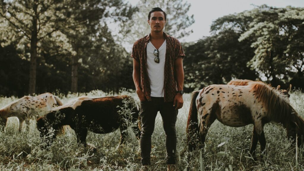 man standing between horse during daytime