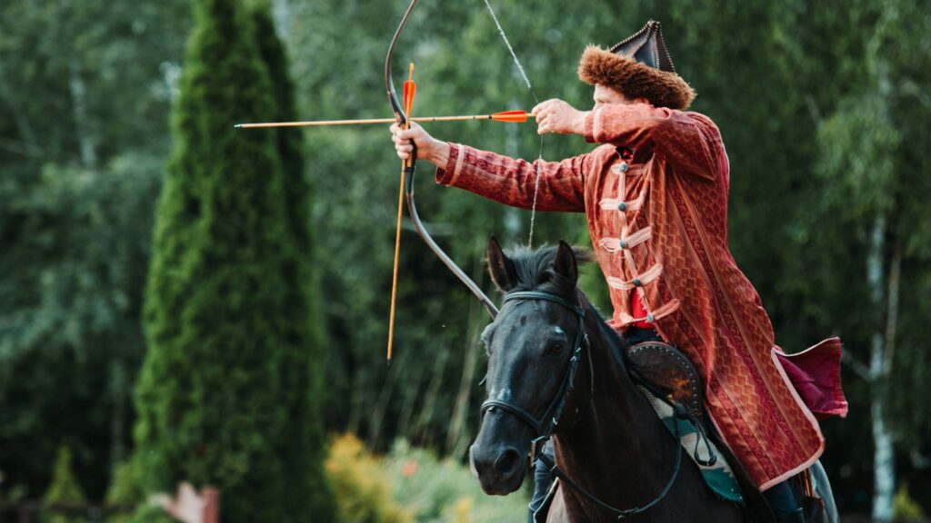 unknown person riding on black horse holding brown compound bow