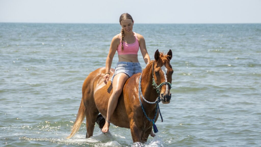 A woman riding a horse through the ocean