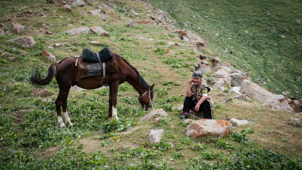 woman in black jacket sitting beside brown horse during daytime