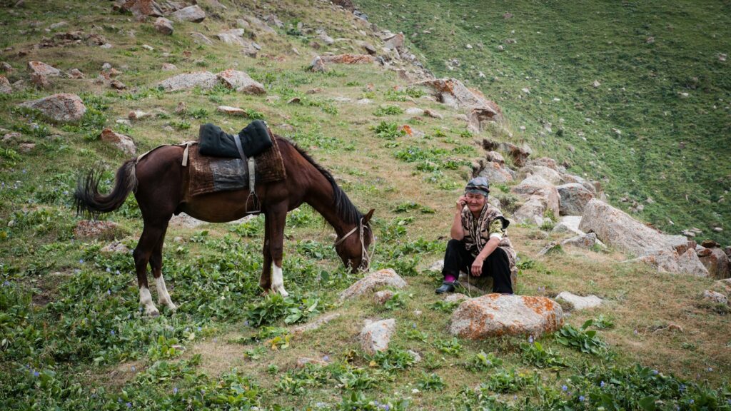 woman in black jacket sitting beside brown horse during daytime
