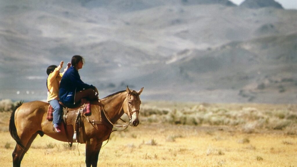 a couple of people riding on the back of a brown horse