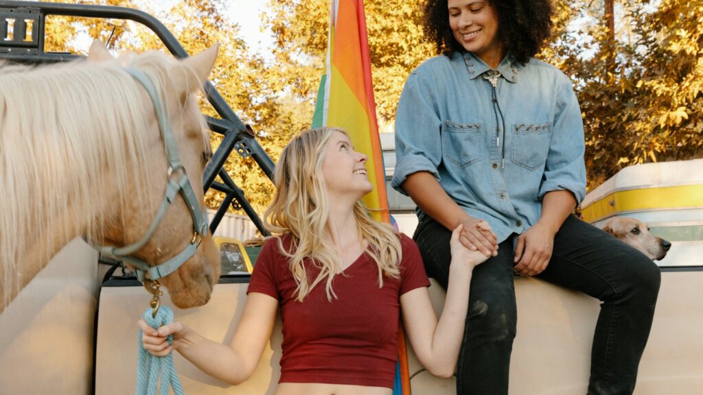 2 women sitting on black and brown horse