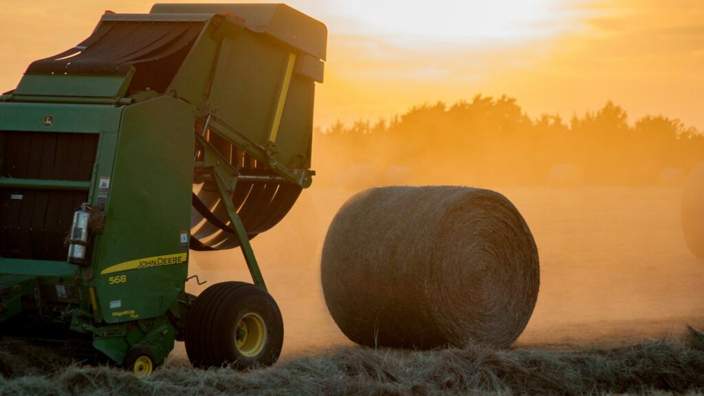 green heavy equipment and hay roll