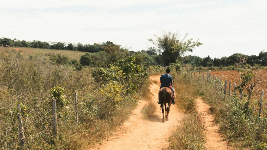 man in red shirt riding on bicycle on dirt road during daytime