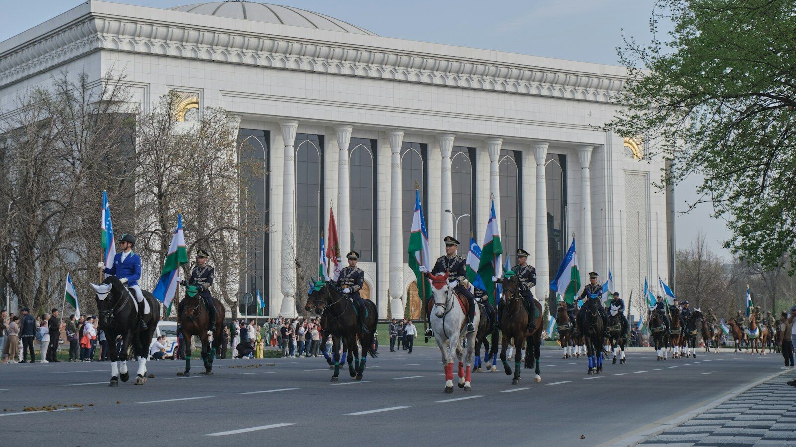 People ride horses in front of a grand building.