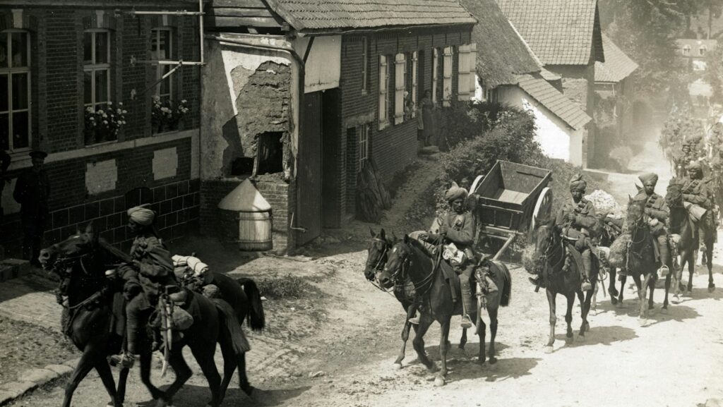 people riding horse beside houses grayscale photography