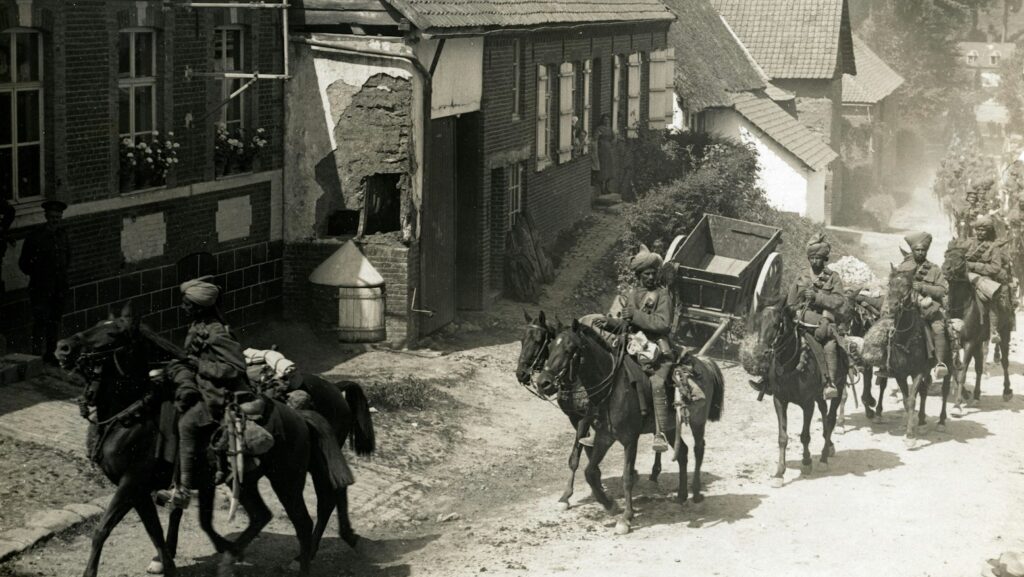 people riding horse beside houses grayscale photography