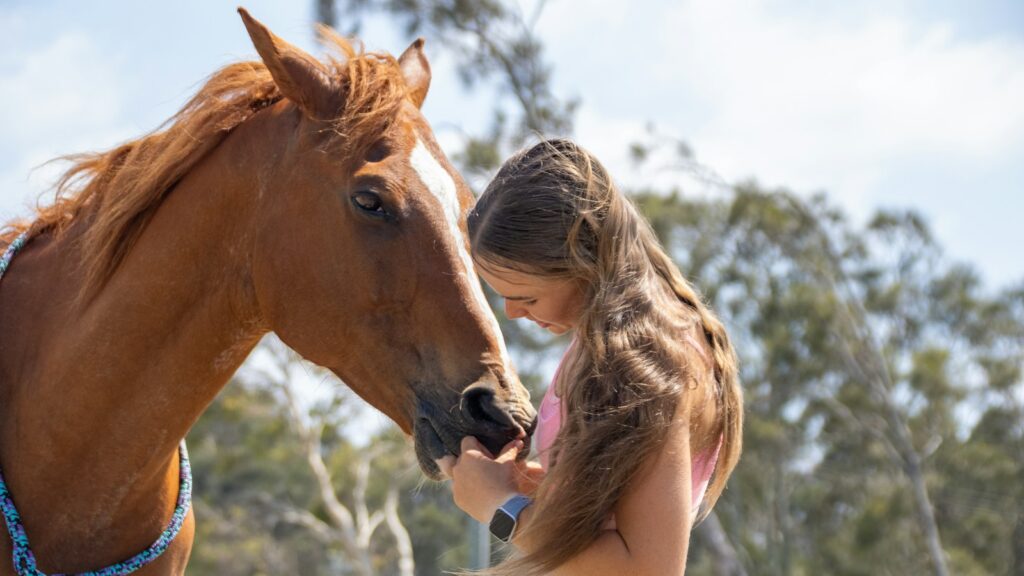 Two young girls petting a horse on the nose