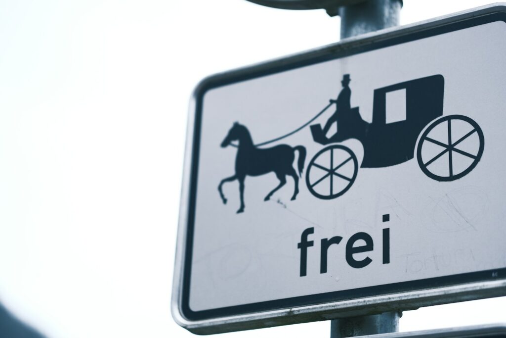A street sign with a horse drawn carriage