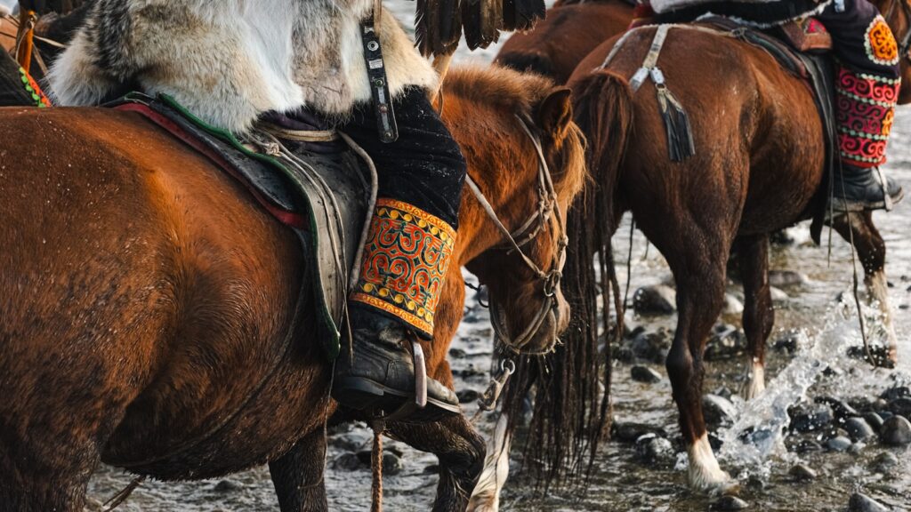 People ride horses across a shallow body of water.